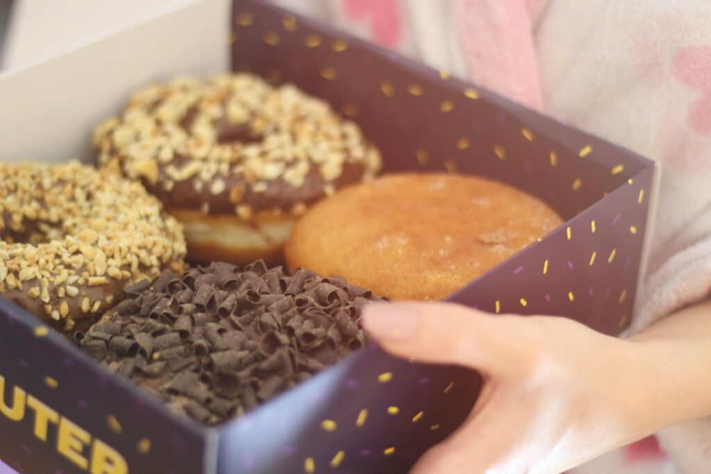 A box of assorted chocolate and nut-covered donuts, ideal for breakfast or dessert.