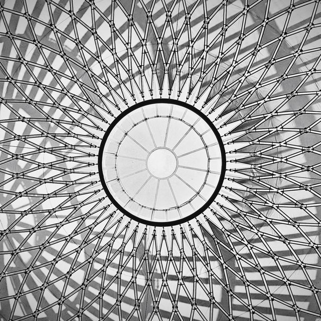 Black and white photo of a dome ceiling featuring a symmetrical geometric pattern with radiating lines.
